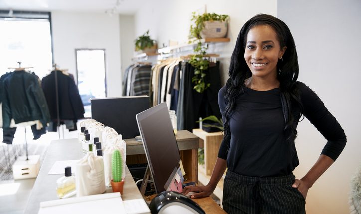 Female assistant smiling behind the counter in clothes store